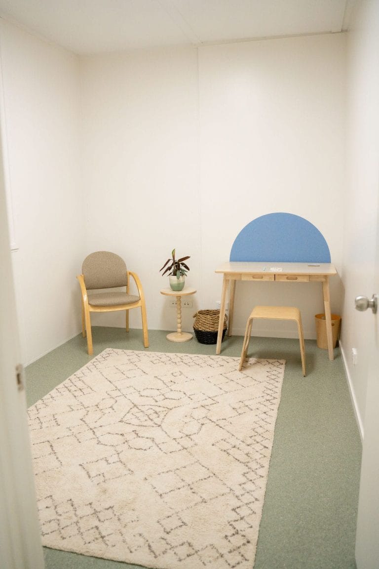 A room with a chair, desk and rug.