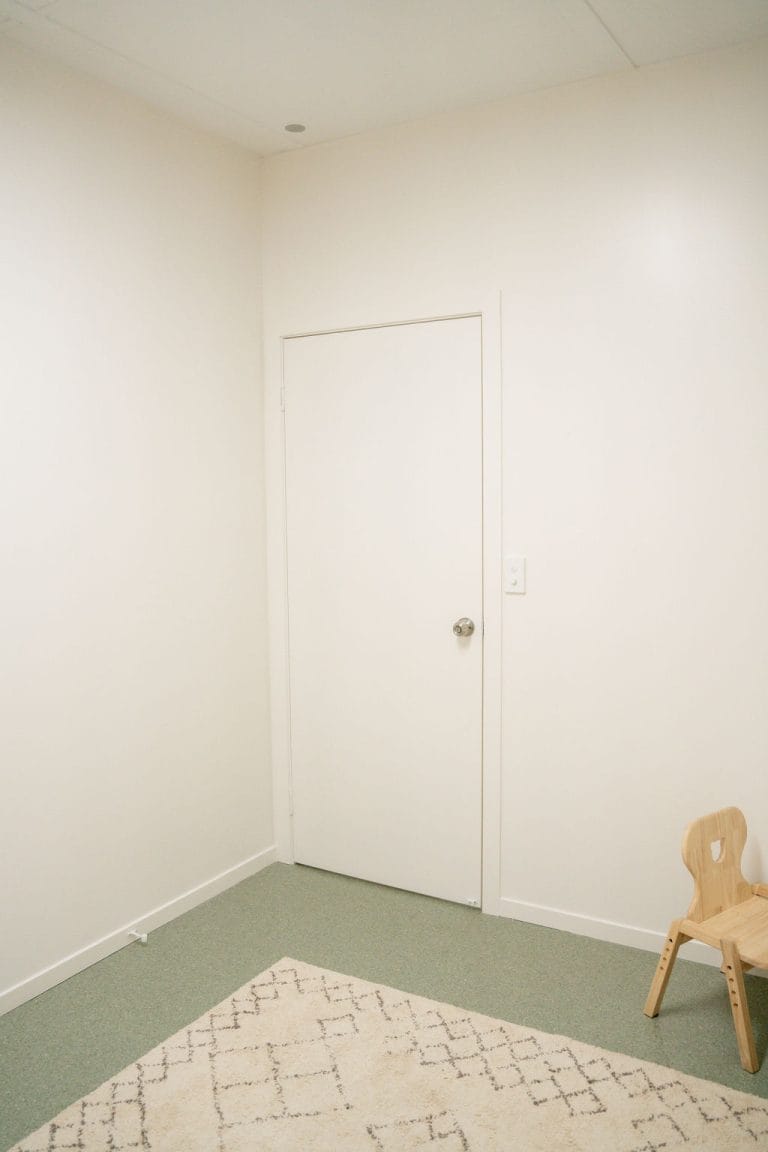 A small room with a chair and a rug.