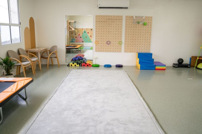 A child's playroom with toys and a rug.
