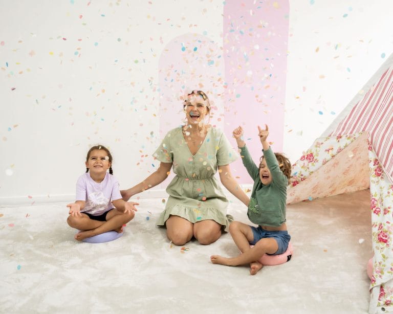 children with a paediatic physiotherapist sitting on a rug throwing confetti